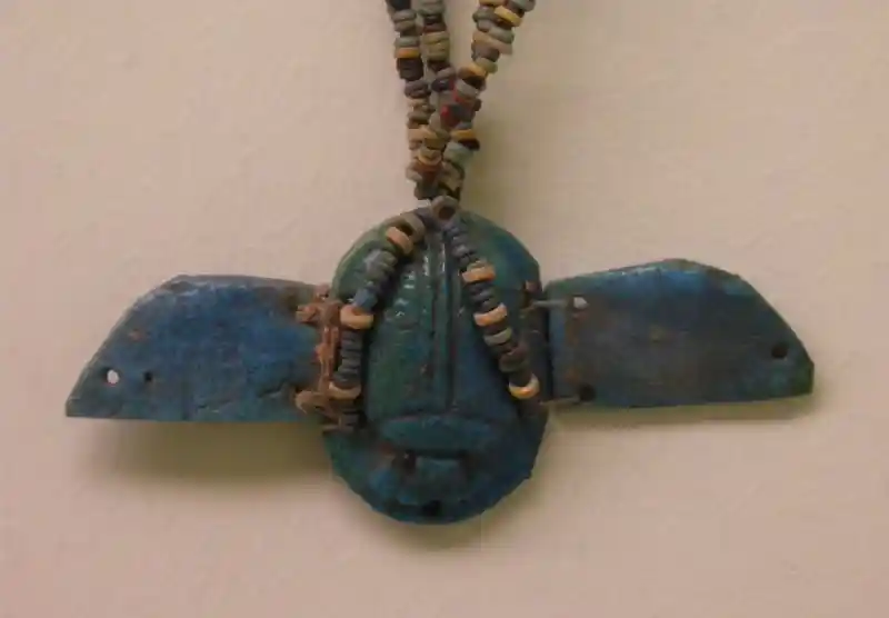 A winged disc pendant secured with colorful beads on top